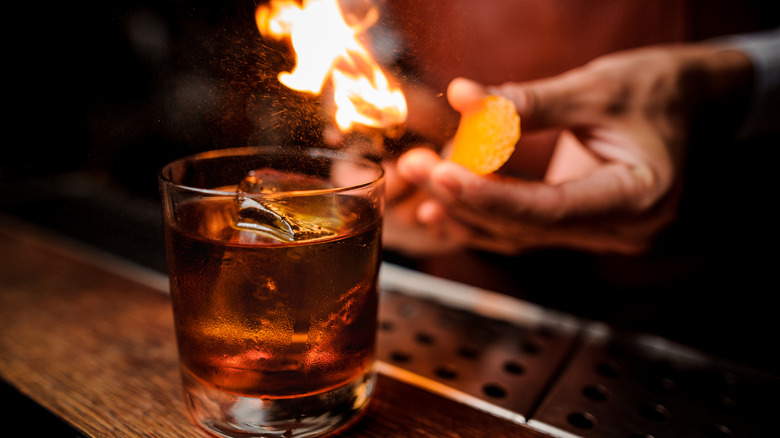 Bartender torching a cinnamon stick over an Old Fashioned